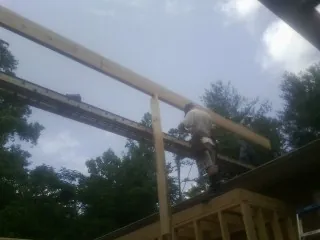 Carpenter setting a ridge beam over a new addition frame — Ice Dam Removal by Roofing Brothers in Ronda