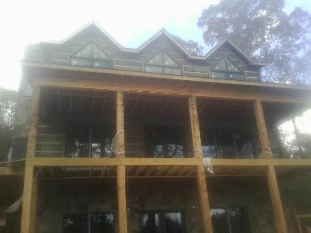 Dormers and porch framing on a large log home under construction — Roof Coating work by our crew in Ronda