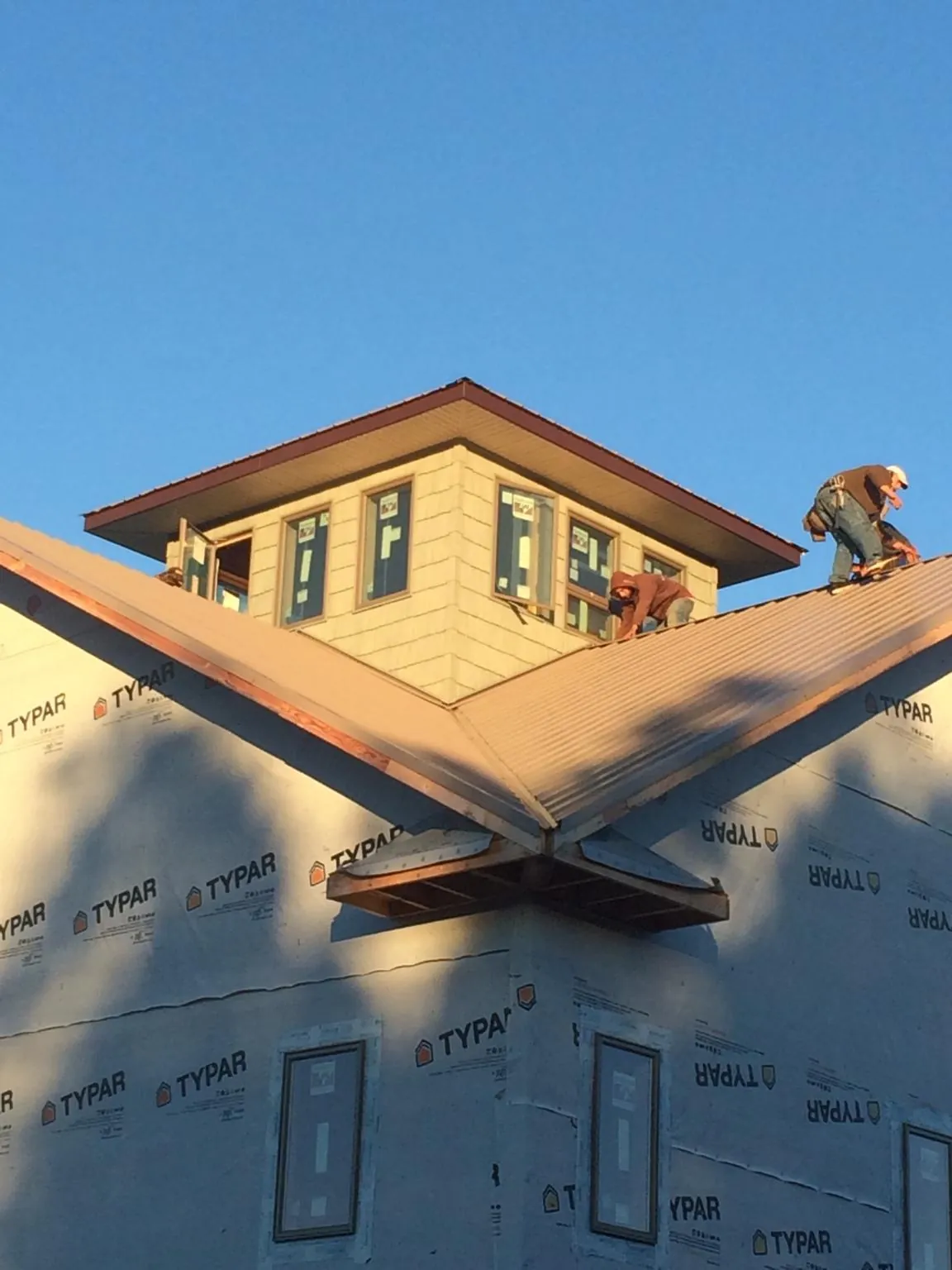 Roofers working around a rooftop cupola on a new metal roof at sunset — Roof Waterproofing in Ronda by Roofing Brothers